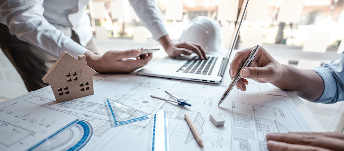 Architects or engineering team consulting and analyzing working on objects tools and construction drawings inspection planning new architectural project on blueprint and model house in modern office